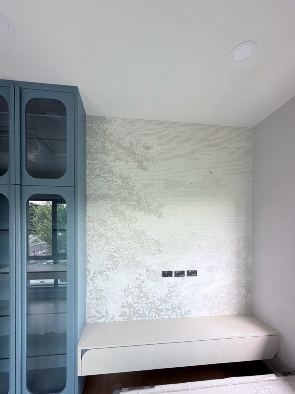 Pale tone-on-tone landscape mural in a study nook beside a blue cabinet