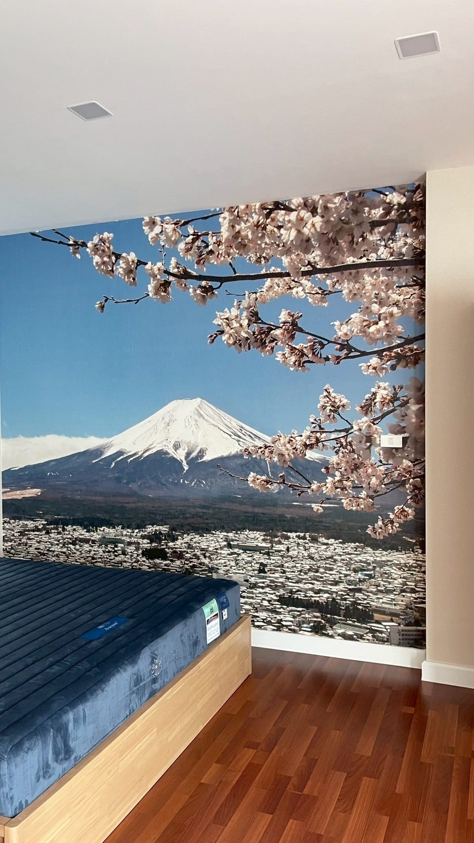 Full-wall Mount Fuji and cherry blossom mural behind a bed